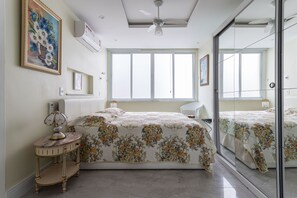 A bedroom with a bed, a bedside table, a mirror, and a ceiling fan. - Ipanema 2 bedrooms lagoon and beach (Ipanema)