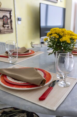 A dining table set with plates, cutlery, and a vase of yellow flowers. - Ipanema 2 bedrooms lagoon and beach (Ipanema)