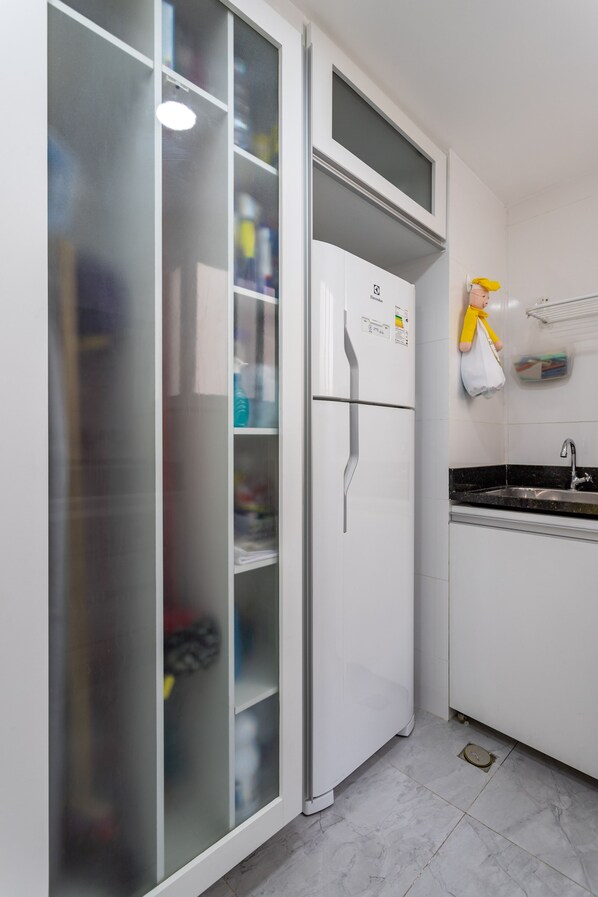 A kitchen with a white refrigerator, a sink, and a cabinet with a glass door. - Ipanema 2 bedrooms lagoon and beach (Ipanema)