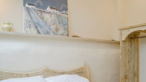 A bed with white bedding and a wooden headboard, a painting on the wall, and a rustic wooden structure to the right. - Dutch Barn One - UK12872 (Ymwlch, near Porthmadog)