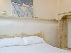A bed with white bedding and a wooden headboard, a painting on the wall, and a rustic wooden structure to the right. - Dutch Barn One - UK12872 (Ymwlch, near Porthmadog)