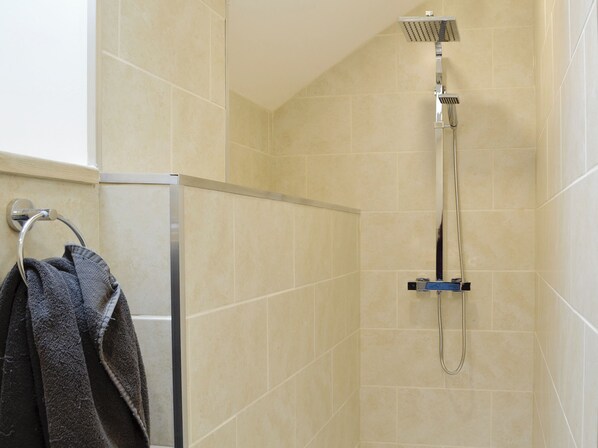 A shower with a handheld showerhead and a wall-mounted control panel.