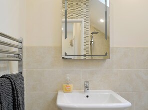 A bathroom with a white sink, a mirror, and a towel rack.