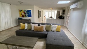 A modern living room with a sectional sofa, a coffee table, and a dining area in the background. - Paradise Haven in Palmas del Mar, a charming house for the perfect vacations! (Humacao)