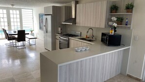 A modern kitchen with a central island, stainless steel appliances, and light wood cabinetry. - Paradise Haven in Palmas del Mar, a charming house for the perfect vacations! (Humacao)