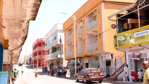 A street with buildings, a car, and people.