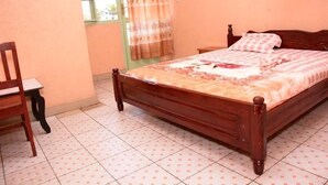 A bedroom with a wooden bed, a chair, and a window with curtains.