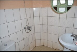 A bathroom with white tiled walls, a toilet, a sink, and a shower with a green window. - Eden Condo Hotel (Muhoza)