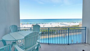 A balcony with a view of a beach and a pool.