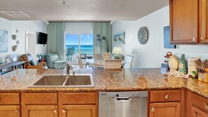 A spacious kitchen with granite countertops, wooden cabinets, and a stainless steel dishwasher.