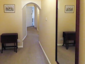 A hallway with carpeted floors, a door at the end, and two framed pictures on the walls. - What more could you ask for than a spacious family home in a rural haven. (Yanwath, near Penrith)