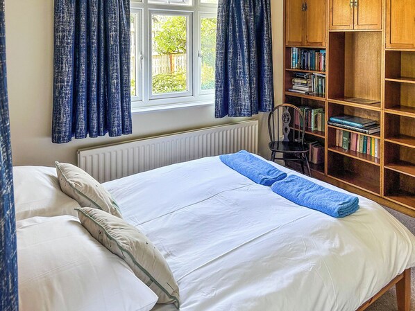 A bedroom with a bed, a radiator, a window with curtains, and a bookshelf. - What more could you ask for than a spacious family home in a rural haven. (Yanwath, near Penrith)