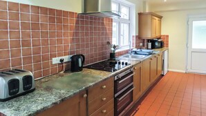 Una cocina con salpicadero de azulejos, estufa, microondas y tostadora.