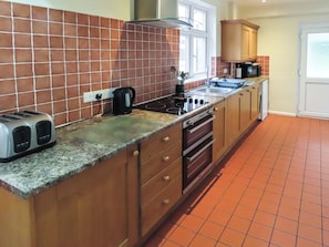 A kitchen with a tiled backsplash, a stove, a microwave, and a toaster. - What more could you ask for than a spacious family home in a rural haven. (Yanwath, near Penrith)