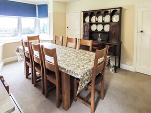 A dining room with a table set for six, surrounded by wooden chairs, a floral tablecloth, and a china cabinet with plates. - What more could you ask for than a spacious family home in a rural haven. (Yanwath, near Penrith)