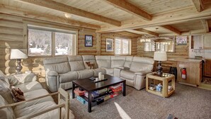 L’intérieur d’une cabane en rondins, avec un canapé d’angle, une table basse et une petite table d’appoint.