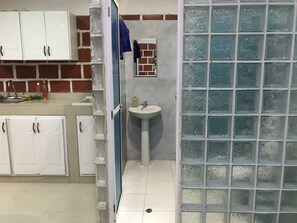 A bathroom with a sink, a mirror, and a glass shower enclosure. - Loft Two (Cali)