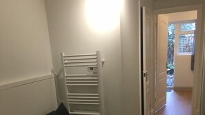 Ein schmaler Flur mit einem dunkelgrauen Sofa und einem weißen Heizkörper.