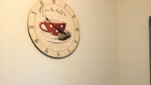 Eine Küche mit Wanduhr, Toaster, Kaffeemaschine und zwei Barhocker.