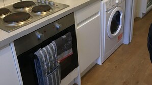 Eine kleine Küche mit Mikrowelle, Backofen und Waschmaschine.