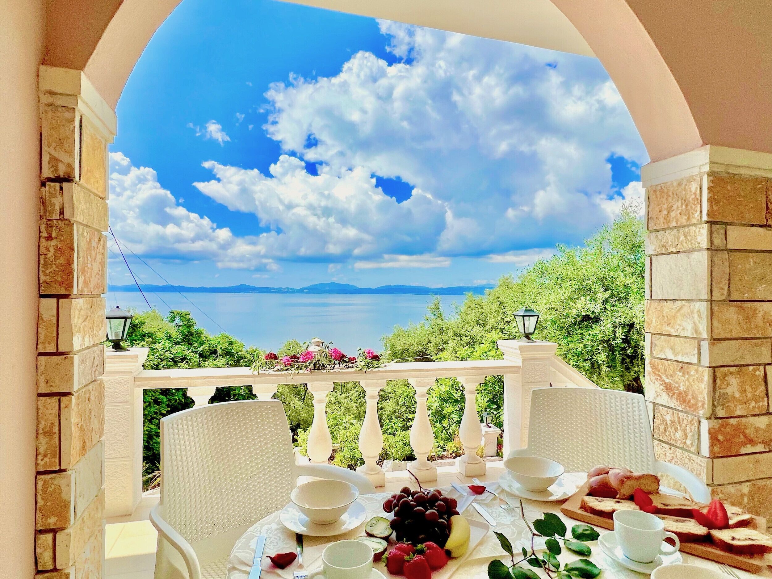A dining area with a table set for two, overlooking a scenic view of a lake and mountains.