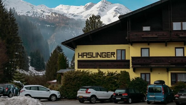 Un edificio con un letrero que dice "HASLINGER" al frente de un paisaje montañoso.