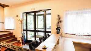 Un comedor con una larga mesa de madera, sillas de cuero negro y vistas amplias a través de grandes ventanales.