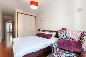 Une chambre d’hôtel avec un lit, une chaise, une armoire et un luminaire au plafond.
