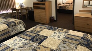A hotel room with two beds, a desk, a television, and a small cabinet. - Dutch Country Inn (Kalona)