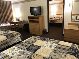 Habitación de hotel con dos camas, un escritorio, un televisor y un mueble bajo.