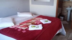 Una habitación de hotel con una cama, un edredón rojo y toallas sobre la cama.