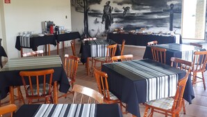 Un área de comedor con mesas y sillas, un mural en la pared y una ventana.