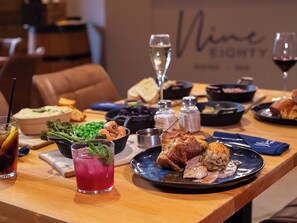A dining table with various dishes, including a roasted chicken, vegetables, and a glass of red drink.
