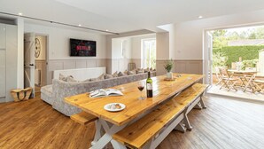 Ein modernes Wohnzimmer mit einem Holzesstisch, einer Couch und einem an der Wand montierten Fernseher.