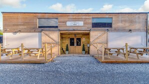 Ein hölzernes Scheunenhaus mit Kiesauffahrt und Picknicktischen.