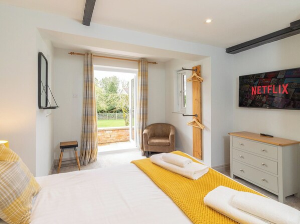 A bedroom with a bed, a chair, a TV, and a window.