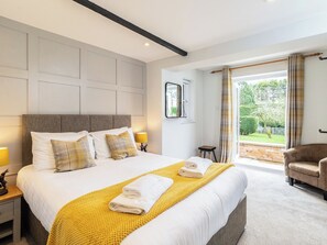 A hotel room with a large bed, a small table, a chair, and a view of the outdoors. - Dovecote House-UK30233 (Cayton, near Scarborough)