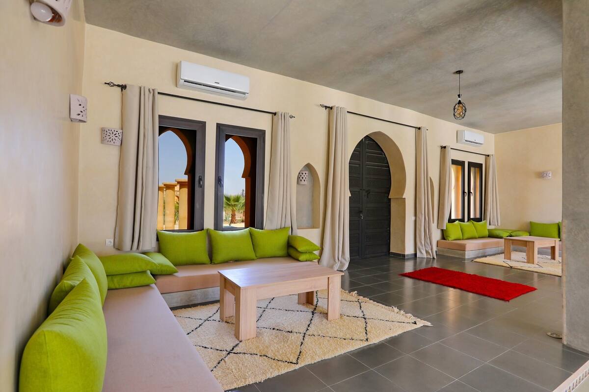 Uma sala de estar ampla com sofá, mesa de centro e tapete vermelho.