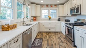 Una cucina moderna con mobili bianchi, un piano cottura in acciaio inossidabile e un pavimento in legno.