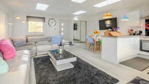 A modern living room with a sofa, coffee table, and a dining area with chairs. - 2 bedroom accommodation in Caldercruix, near Airdrie (Caldercruix, near Airdrie)