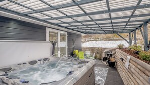 A covered outdoor area with a hot tub, seating, and a view of a snowy landscape. - 2 bedroom accommodation in Caldercruix, near Airdrie (Caldercruix, near Airdrie)