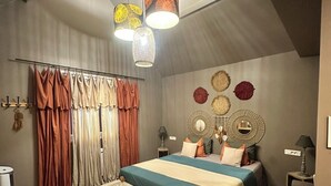 A bedroom with a large bed, a bench, a hanging light fixture, and a wall with decorative items. - J&J Room - Exceptional accommodation near Provins. www.jj-accommodation.fr (Saint-Loup-de-Naud)