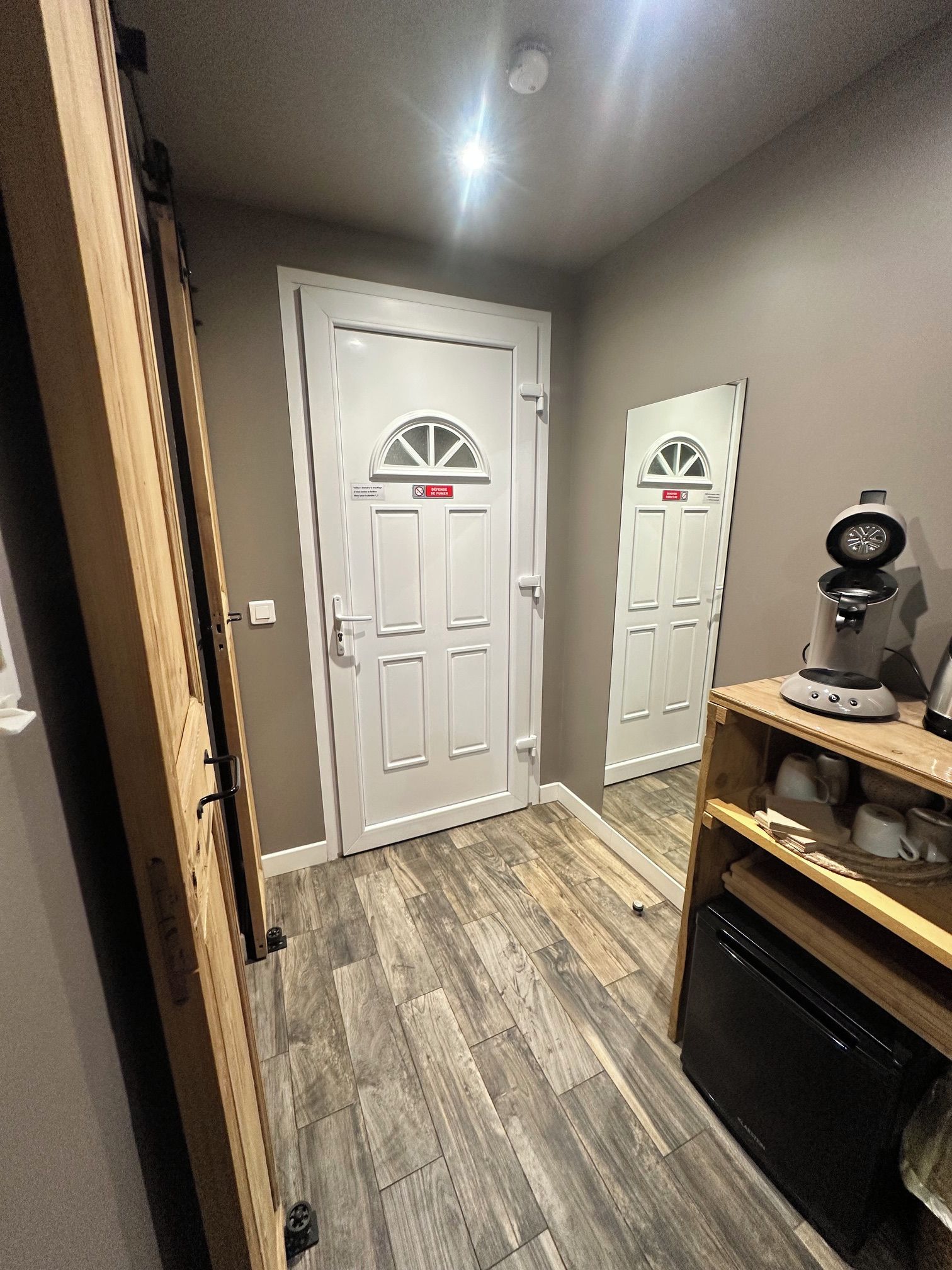A hallway with two white doors, a coffee maker, and a dishwasher.