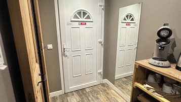 A hallway with two white doors, a coffee maker, and a dishwasher.