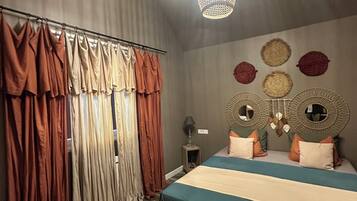 Une chambre à coucher avec un lit, des rideaux, une tête de lit agrémentée de miroirs et des lampes suspendues.