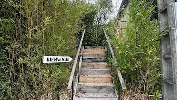 Een houten trap die leidt naar de ingang van een gebouw, met een 'BIENVENUE' bord.