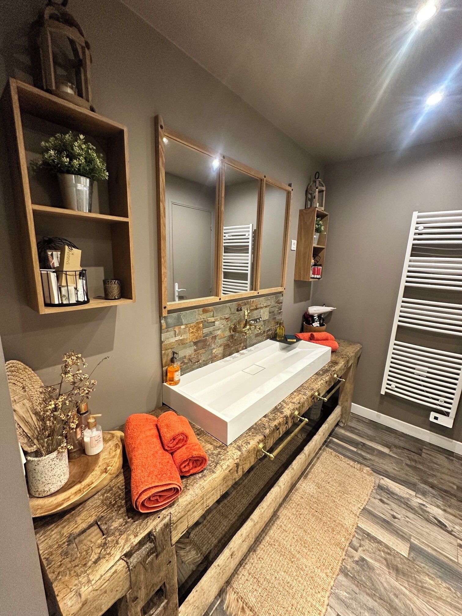 A modern bathroom with a large white sink, wooden vanity, and a mirror above it.