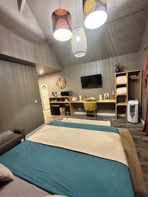 Ein modernes Schlafzimmer mit einem Bett, einem Schreibtisch und einem Fernseher.