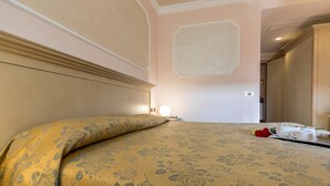 Une chambre d’hôtel avec un lit, une table de chevet, une lampe de chevet et une couvre-lit à motifs floraux.