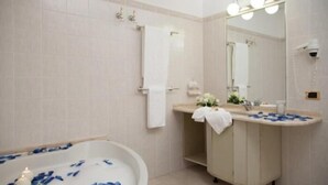 Une salle de bain équipée d’une baignoire, d’un lavabo, d’un miroir et d’un porte-serviettes.